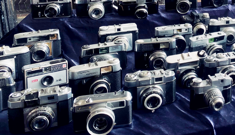 Photograph of vintage cameras laid out on navy blue velvet on a market stall on Portobello Road